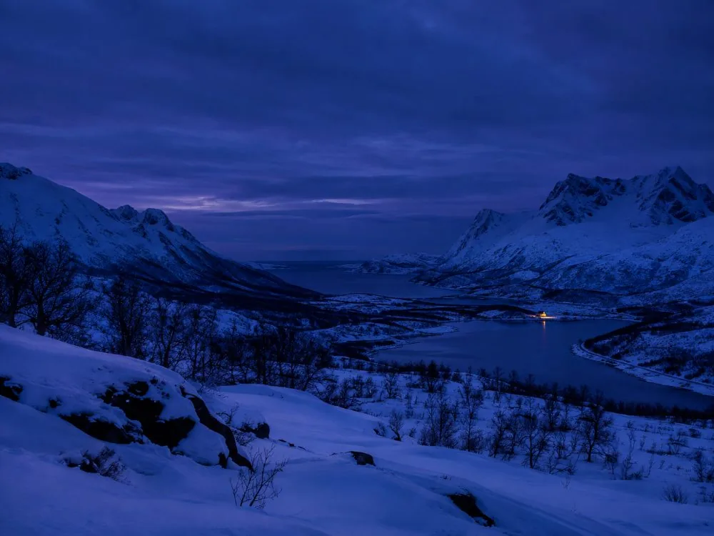 Blue midday twilight over a snowbound valley during the polar night